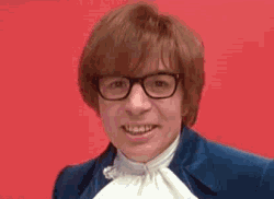 Austin Powers in a blue velvet suit grins, shouts with his mouth wide open, then leans in close to the camera